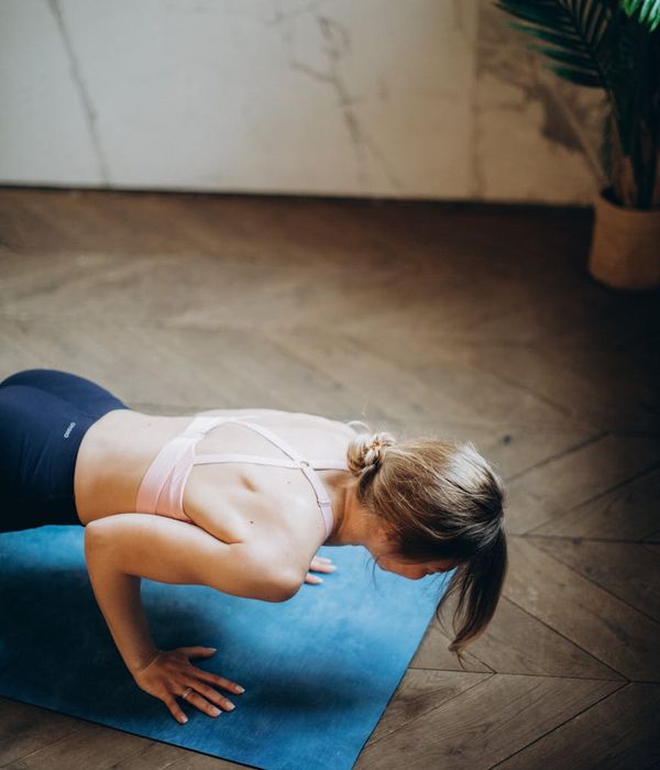 Woman holding a serene yoga balance pose in a dark room.